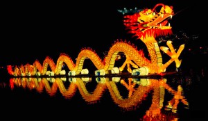 A dragon-shaped lantern is lit up in a lake at a temple fair in Kunming